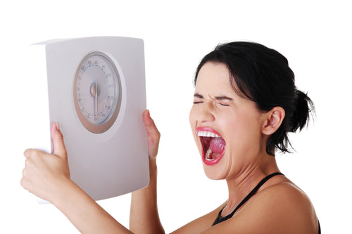 Frustrated woman with scale, isolated on white