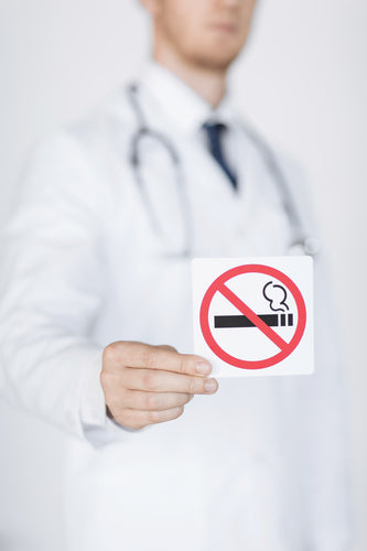 close up of doctor holding no smoking sign in hands