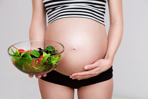 Healthy nutrition and pregnancy. Close-up pregnant woman's belly and vegetable salad