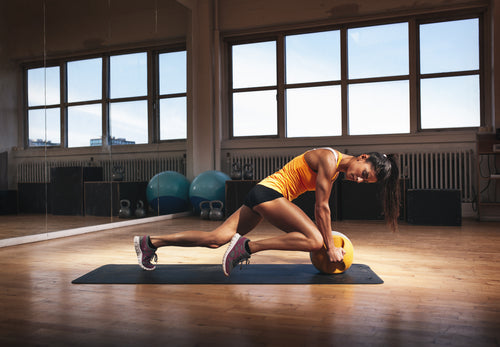 Muscular woman in gym working out on her core body. Strong woman exercising with kettlebell in sports club.